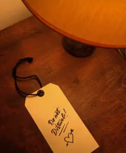 Étiquette de chambre de l'Hôtel Amour à Nice photographiée sur une table en bois, illustrant le rôle des détails dans l'identité visuelle d'un lieu.