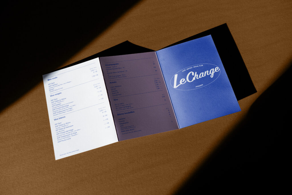 Menu dépliant ouvert du Change, avec couverture bleue et pages intérieures claires.
